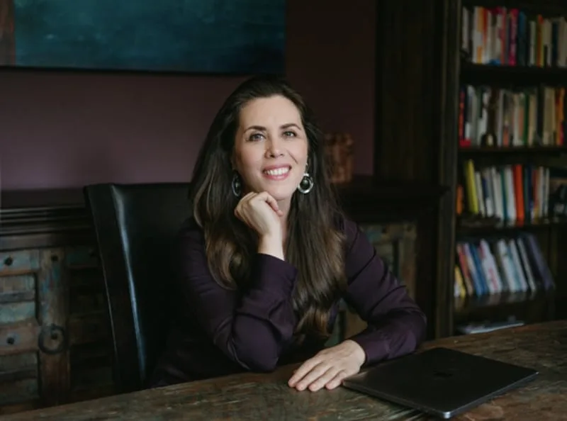 La Dra. Claire Zammit sentada en una mesa con la mano en la barbilla.